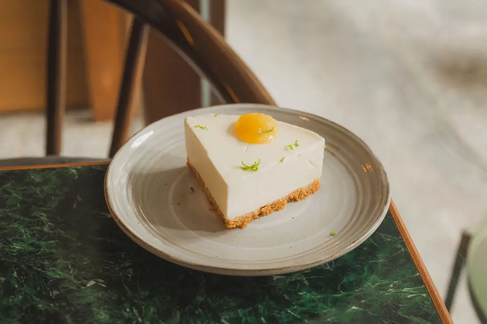 Foto contoh dari Pexels: potongan cheesecake dengan parutan kulit jeruk nipis di piring putih — bukan produk itsumō TART
