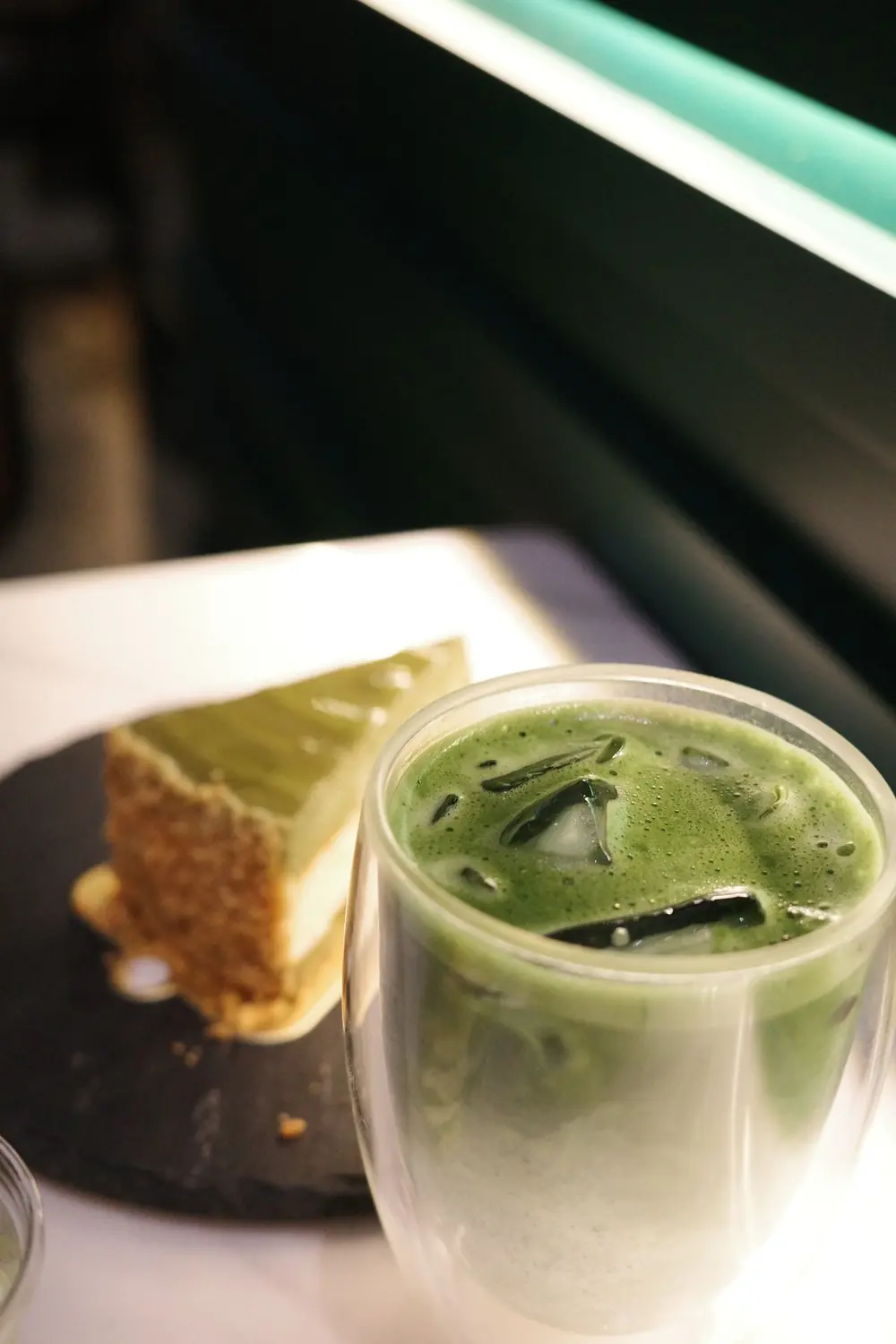 Foto contoh dari Pexels: segelas es matcha latte di depan potongan cheesecake matcha — bukan produk itsumō TART